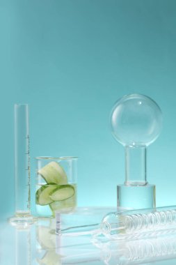 Yoğunlaştırıcı, hacim silindiri ve içinde salatalık dilimleri olan bir beher kabı mavi bir arkaplana karşı. Salatalık (salatalık sativus) bir nem kaynağıdır ve vücudun detoks yapmasına yardımcı olur.