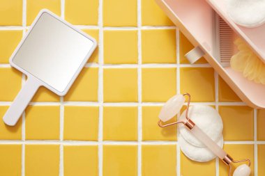 Pamuk pedlerle dizilmiş bir el aynası, gül kuvars yüz masajı silindiri ve çekmeceli mini plastik bir kutu. Güzellik ürünlerinin tanıtımı için mozaik fayanslarda boş alan