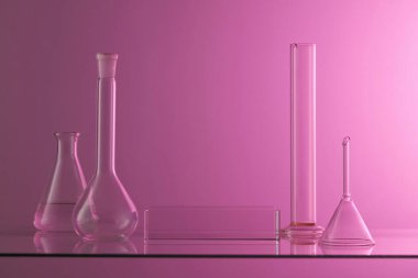 Birkaç şişe, cam huni ve tüp ile laboratuvar konsepti. Ürün tanıtımı için boş alanı olan dikdörtgen şeklinde şeffaf bir podyum