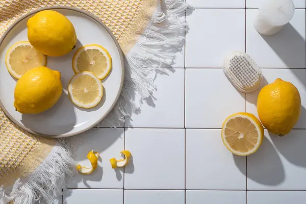 A dish of Lemon slices placed on a wool scarf decorated with candle and a scrub brush. Blank space for product presentation. Copy space. The benefits of Lemon (Citrus limon) for skin are numerous