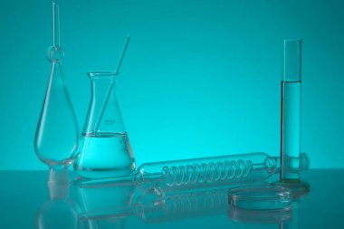 Mavi arka planda, Erlenmeyer şişesi, içinde spiral boru bulunan bir tüp, test tüpü ve bir petri kabı var. Laboratuvar deneyimi ve araştırması