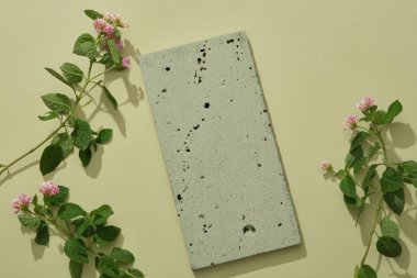 An empty stone podium in gray color decorated with some Lantana camara flowers over a light background. Blank space for product promotion. Natural concept clipart