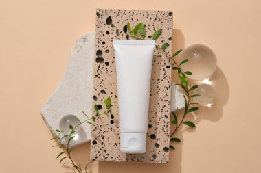 Etiketsiz beyaz melodi dikdörtgen taş podyuma konuldu ve yeşil yapraklarla süslendi ve birkaç büyük cam top ile süslendi. Cilt Temizleme Ürün Model