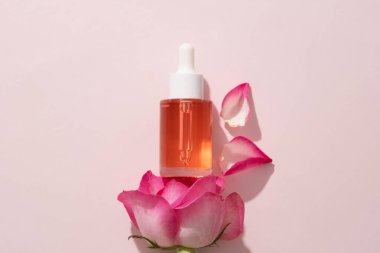 Rose 'dan çıkarılmış pembe sıvı içeren damlatılmamış cam şişe. Rose 'un (Rosa) hem cilt hem de sağlık için birçok faydası vardır.