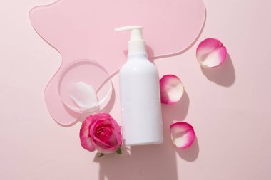 Üzerinde etiketsiz pompa şişesi olan, geometrik akrilik çarşaflı, krem desenli, şeffaf bir podyum. Rose serbest radikal hasara karşı korumaya yardım ediyor