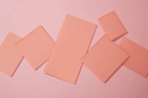 Some pink acrylic sheets in rectangle and square shape are decorated on pastel background. Blank space for beauty and skin care product presentation