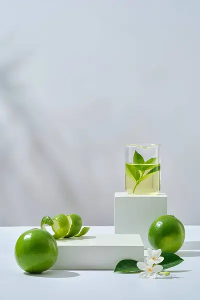 액체와 잎으로 껍질과 꽃으로 Citrus Aurantiifolia 제품을 표시하기 포디움에 진열장 — 스톡 사진