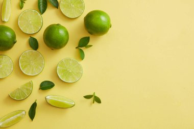 Limon dilimleri ve yeşil yapraklar sol tarafta güzelce düzenlenmiş. Lime (Citrus aurantiifolia) reklamı için sol tarafta boş alan