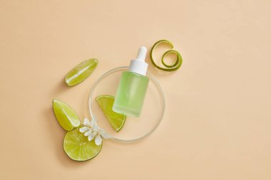 İçinde yeşil sıvı bulunan, limon dilimli, yuvarlak, şeffaf bir podyum. Limonlu güzellik ürünü (Citrus aurantiifolia) özeti