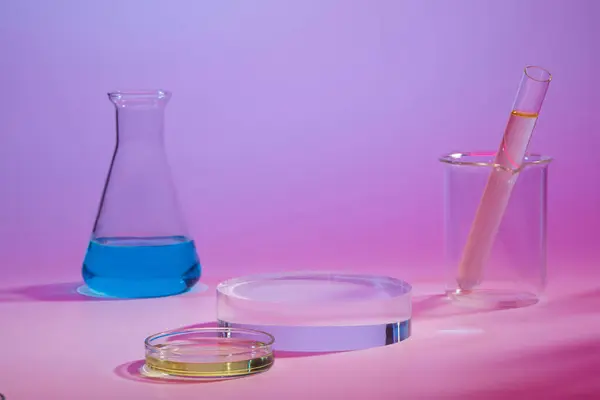 Front view of colorful liquid filled inside conical flask, test tube and a petri dish. Pedestal or platform for beauty products presentation