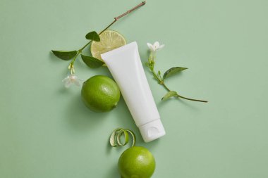 Beyaz bir tüpün üst görüntüsü. Üzerinde limon ve beyaz çiçek dallarıyla süslenmiş boş bir etiket var. Limon (Citrus aurantiifolia) kozmetik üretiminde malzeme olarak kullanılır.