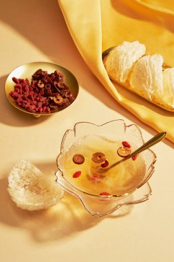 Sarı kumaş üzerine yerleştirilmiş yenilebilir kuş yuvası, cam bir kase kuş yuvası çorbası, altın bir tabak kurutulmuş goji üzümü ve jujube. Kuş yuvası Güneydoğu Asya 'da çok iyi bilinir.