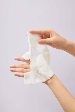 Zarif bir kadın el modeli arka planda maske tutuyor. Ön manzara. Yüz güzelliği maskeleri, günlük bakım rutinleri.