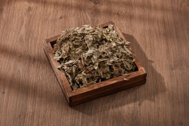 Üzerinde Mugwort olan ahşap bir tabak. Mugwort (Artemisia vulgaris) sindirim problemleri, düzensiz adet ve yüksek tansiyon için tanıtılır.