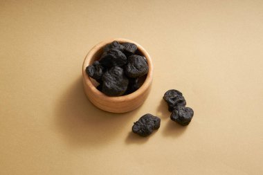 Minimalist bej arkaplanlı Radix rehmanniae. Radix rehmanniae (Rehmannia glutinosa), yüksek kan basıncı, kötü kan, vücut zayıflığı gibi hastalıkların tedavisinde kullanılır.