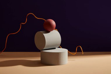 Silindir taş podyum ve koyu arkaplanda pembe bir top. Ürün reklamı için boş alan