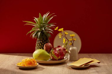 Bir ahşap masa çeşitli meyveler, biraz kurutulmuş şeker ve saksı ile hazırlanır. Çin yeni yılı konsepti. Ön görünüm