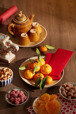 Fındıklı çaydanlık, fındık, mandalina, kırmızı zarflar ve ahşap masada kurutulmuş meyveler.