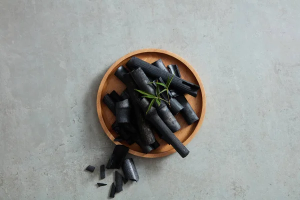 上に黒い竹がついている木製のトレイ トップビュー フラットレイ オーバーヘッド 活性炭から抽出された製品を促進する — ストック写真