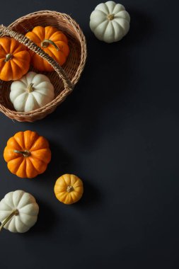 Kahverengi bir sepetin üzerindeki Cadılar Bayramı balkabakları koyu arka planda süslenmiş. Ürün tanıtımı için boş alan