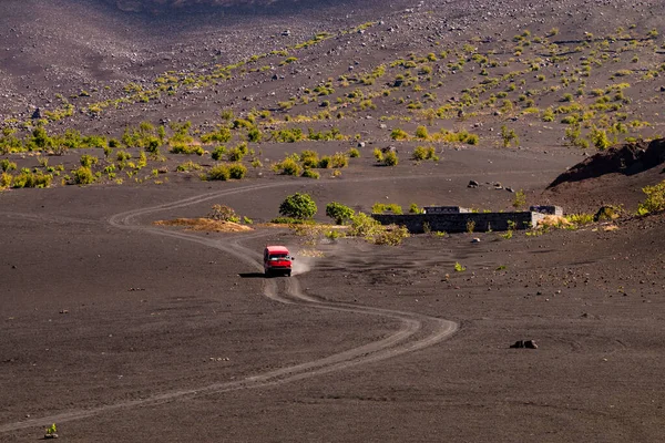 Kırmızı bir minibüs, Pico do Fogo, Cape Verde Adaları 'nın bir kanadında kül yolu boyunca ilerliyor.