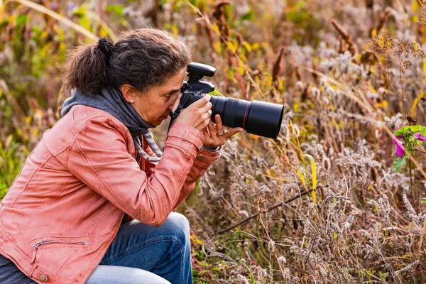 Pretty woman isolated as photographer with professional dslr camera in rural nature in autumn