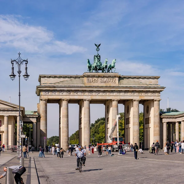 The Brandenburg Gate with street lamp and people as a German landmark under blue sky, Berlin, Germany