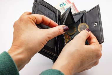 Studio shot of a woman's hands holding a wallet with euro coins and bills and a 2 euro coin