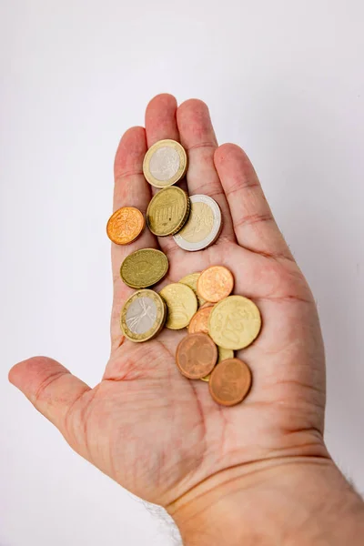 Detail or close-up of a hand with euro coins isolated in the studio against a white background