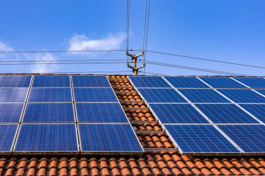 Solanpanel einer Photovoltaik-Anlage auf einem privaten Dach mit Strommast ve Stromkabeln
