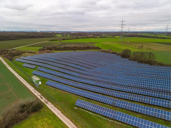 A solar park with PV panels on a farm track in the middle of meadows and fields in a rural region in Hesse, Germany