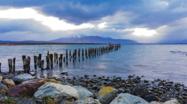 Kuşlar, dramatik bulutlar, Puerto Natales, Şili, Patagonya, Güney Amerika 'daki tarihi yaya köprüsünden uzun zaman önce Muelle Historico