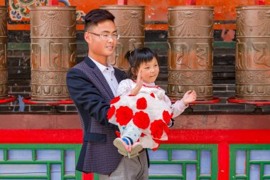 Bir baba ve genç bir kız Kumbum Jampaling manastır kompleksi Xining, Çin 'deki bir tapınağın aniken dua tekerlerinin önünde poz veriyorlar.