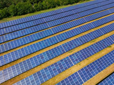 Almanya 'da güneş ışığındaki tarımsal bir alanda sıra sıra fotovoltaik panelleri olan güneş enerjisi santrali