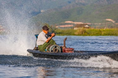Güçlü motorlu bir sürat teknesi olan Birmanyalı bir adam, 12 Nisan 2018 'de Myanmar, Asya' daki cennet gibi Inle Gölü 'nde doğanın önüne çok fazla su sıçrattı.