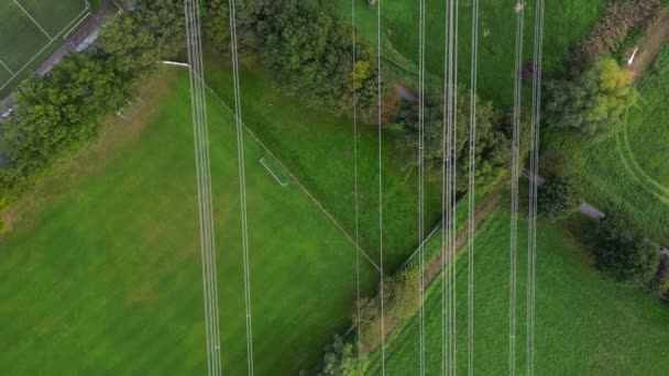 有许多电线的电线杆在有树木和草地的农村地区飞行的无人机图像 — 图库视频影像