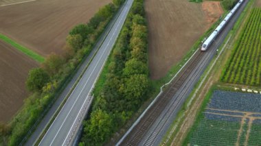 Verkehrswende 'de, Almanya' nın kırsal kesimindeki bir yola paralel giden hızlı bir ICE ekspres treninin hava videosu.
