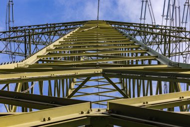 Devasa bir rüzgar geçirgen yüksek voltaj pilonu. Çapraz askılı ve çelikten yapılmış kirişleri var.