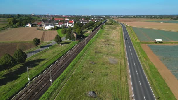 一辆快速Ice特快列车在靠近一个村庄的两条乡间公路旁边行驶 穿过德国的一个农村地区 车上有无人驾驶飞机 — 图库视频影像