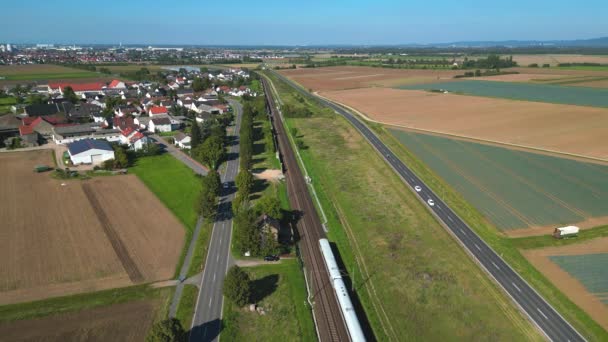 在德国农村 一列快速的Ice火车穿过一条与两条公路平行的铁路线上的一个村庄 — 图库视频影像