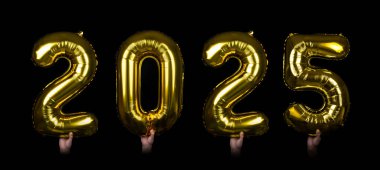 2025 rakamlarını gösteren parıldayan altın balonları tutan eller koyu bir arkaplanda yer alıyor. Yeni yıl kutlamaları, şenlikli etkinlikler ve gelecek temalı tasarımlar için mükemmel..