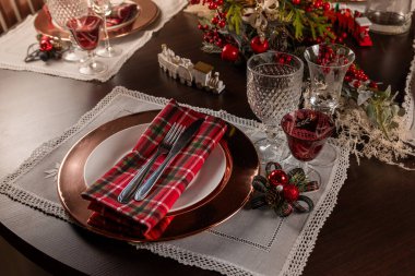 A beautifully decorated Christmas dinner table with festive red accents, elegant glassware, and intricate place settings. The arrangement creates a warm and inviting holiday atmosphere. clipart