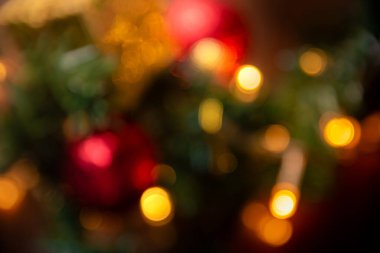 Bulanık Noel ışıkları ve parlak kırmızı ve altın süslemeleri içeren soyut bir resim, tatil temalı projeler için ideal sıcak ve şenlikli bir atmosfer yaratıyor.