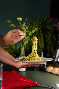 A plate of freshly prepared pasta adorned with a vibrant green sauce and delicate garnishes, emphasizing a fusion of flavors and aesthetics. Ideal for gourmet dining and culinary presentations. clipart