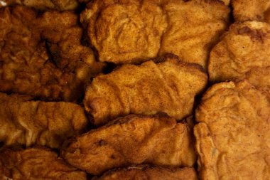 Altın rengi kahverengi kaplamalı kızarmış Milano tavuğunun yakın plan görüntüsü. Doku çıtır çıtır dış görünüşü ön plana çıkarıyor. Ağız sulandırıcı, ev yapımı bir tat uyandırıyor..