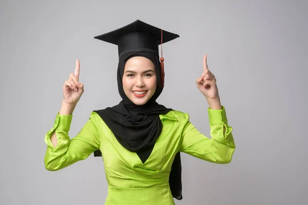 A Young smiling muslim woman with hijab wearing graduation hat, education and university concept