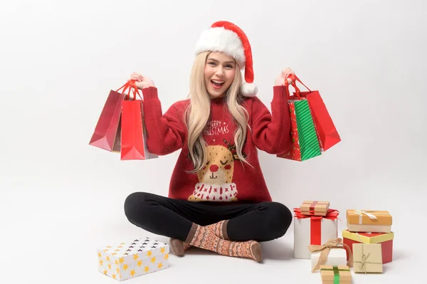 Stock image Portrait of happy Caucasian young woman in santa claus hat with gift box and shopping bags over white background