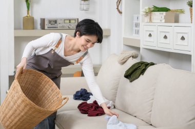 Asyalı genç bir kadın hizmetçi kirli çamaşırlarını sepete atar, evde temizlik için, yaşam tarzı konsepti olarak. 