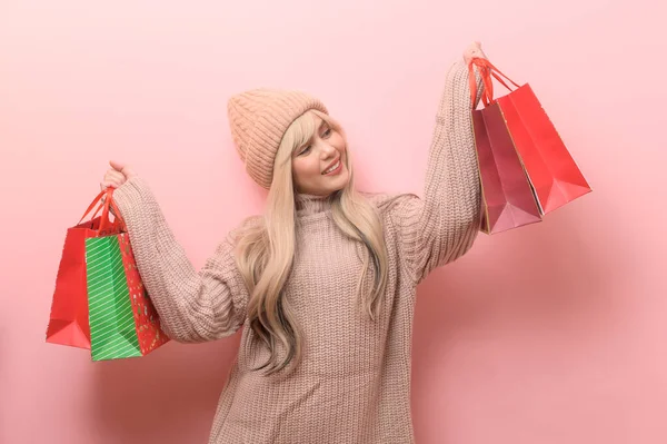 ピンクの背景の上にショッピングバッグを保持セーターを身に着けている白人若い女性の肖像 — ストック写真