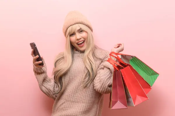 身穿毛衣 提着购物袋 披着粉色背景的白人年轻女子的画像 — 图库照片